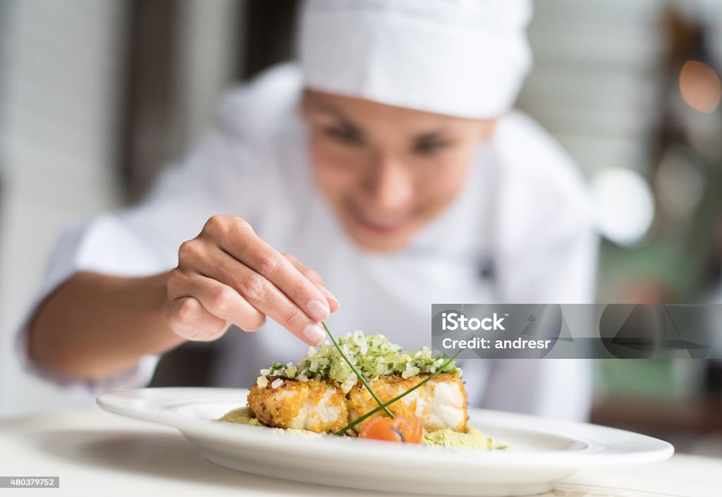 Cook decorating a plate Cook decorating a plate and putting the ultimate touches - focus on foreground Chef Stock Photo