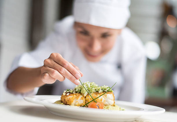 Cook decorating a plate Cook decorating a plate and putting the ultimate touches - focus on foreground chef stock pictures, royalty-free photos & images