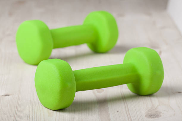 istock small green dumbbells on wooden surface 480381577