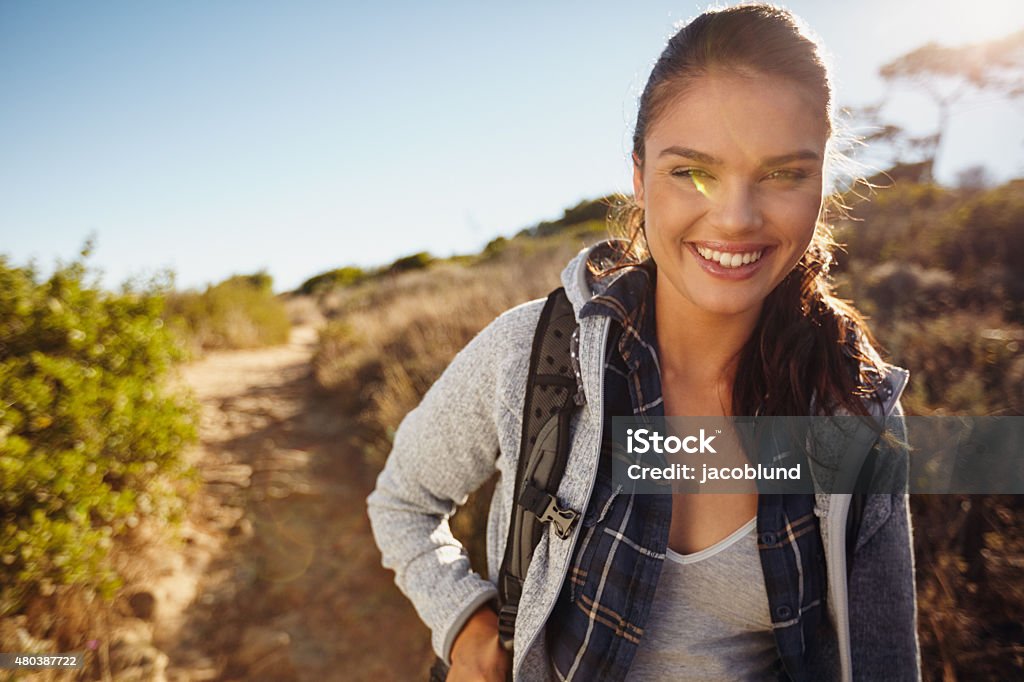 Young female tourist hiking in nature Hiker hiking in nature. Young woman smiling during hike. Caucasian female model outdoors on hike looking at camera. Enjoying summer vacation in countryside. 20-29 Years Stock Photo