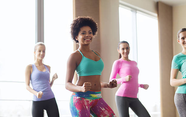 sorridente grupo de pessoas dança no ginásio ou na academia, - african descent american culture exercising women imagens e fotografias de stock