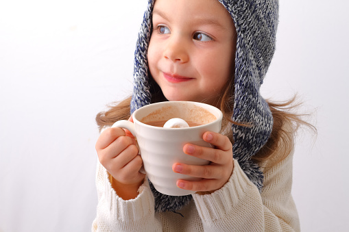 A cute little girl drinking hot chocolate with marshmallow