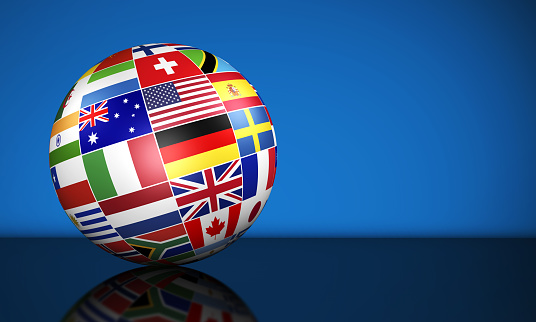 Travel, services, education and international business management concept with a globe and international flags of the world on blue background with copy space.