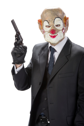 Gangster masked clown with a gun during a robbery isolated on white background