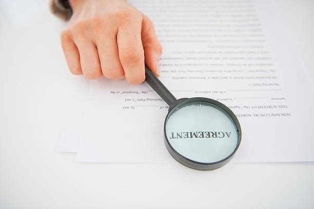 istock Closeup on woman holding magnifying glass in front of document 480403551