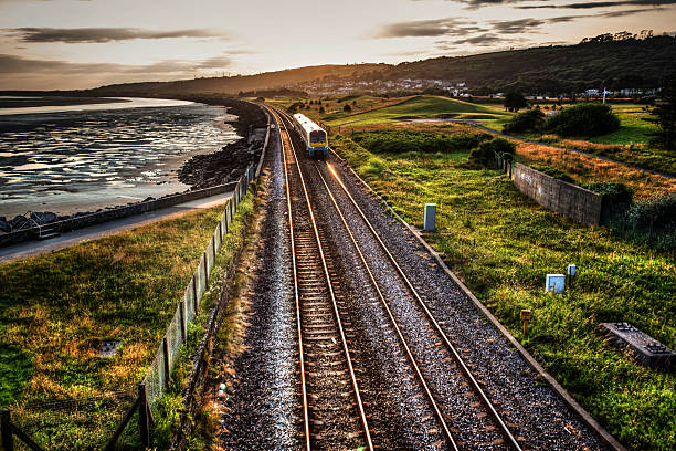 istock Train travelling past sea wall at sunset 480416626
