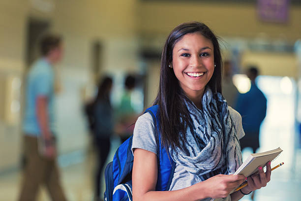 hispânica adolescente feminino estudante do ensino médio sorrindo no corredor - aluna da escola secundária - fotografias e filmes do acervo