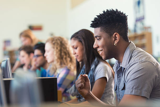 афро-американский колледж студент, улыбающихся во время использования компьютера в библиотеке - computer lab computer training classroom стоковые фото и изображения