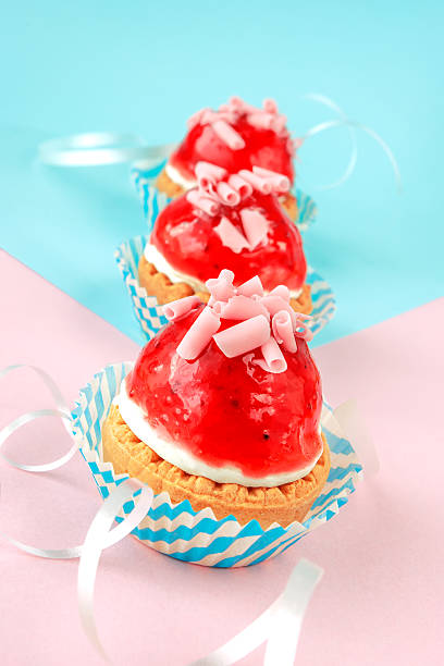 Three little cupcakes with cream and strawberry glaze stock photo