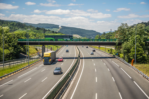 A hihgway view with trucks, cars and even a bus crossing it through a bridge.