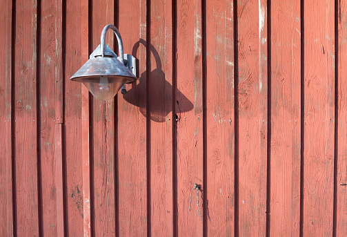 Rustic lamp of metal on red wooden wall with copy space.