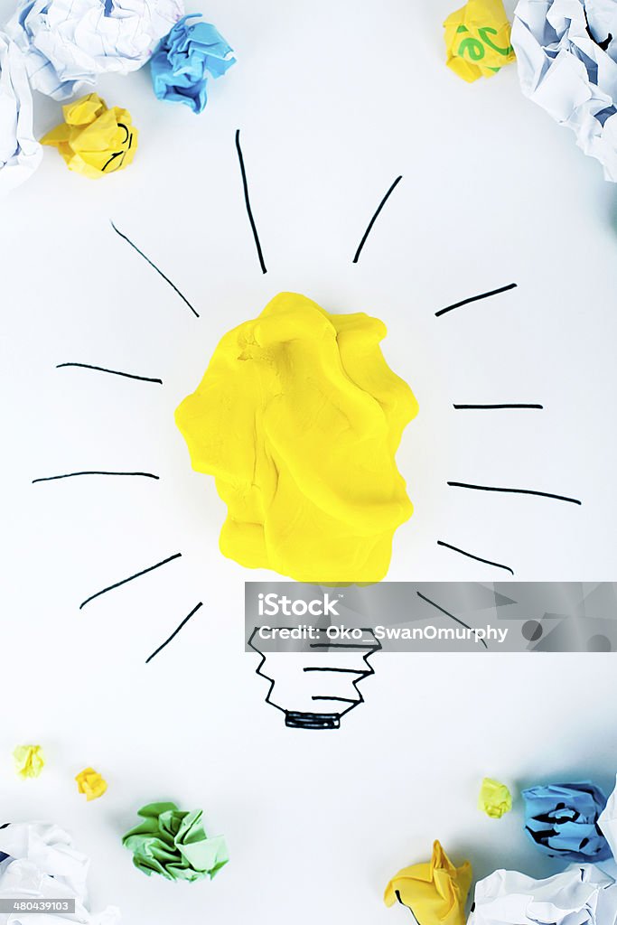 Brand New Idea Having a good idea concept - yellow play clay as light bulb, paper balls around Forecasting Stock Photo