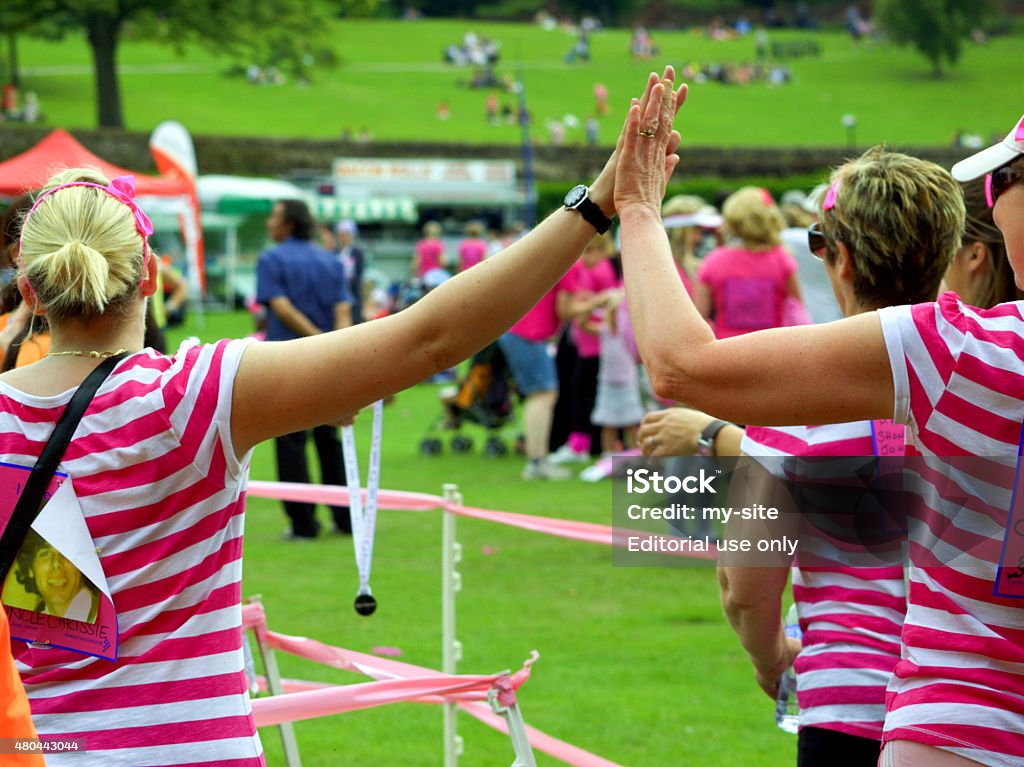 Two friends high fiving at the end of a race. Colchester, Essex, England,UK- 3 July 2011-two friend doing a three legged race at the annual race for life event, raising money for cancer research UK. Fundraising Stock Photo