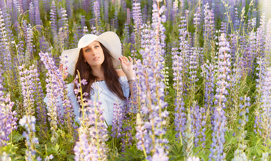 Fashionable young woman wearing a white hat and shirt, summery meadow