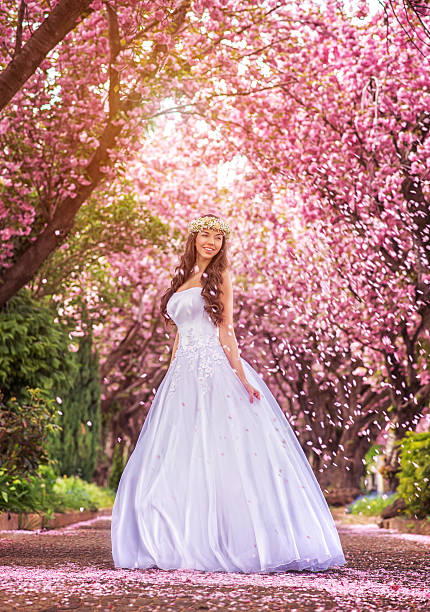 istock Beautiful bride under the sakura tree and flower petals 480457874