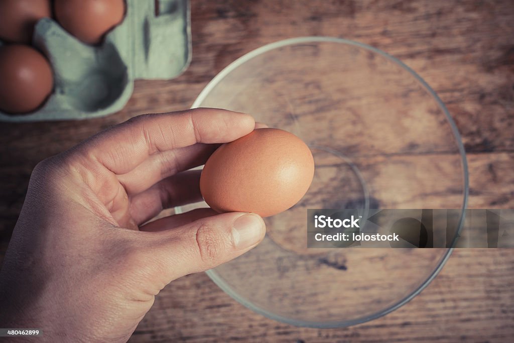 Hand cracking egg Hand holding an egg and preparing to crack it into a bowl Adult Stock Photo