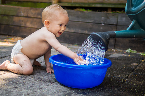 adorable baby playing with water outdoors