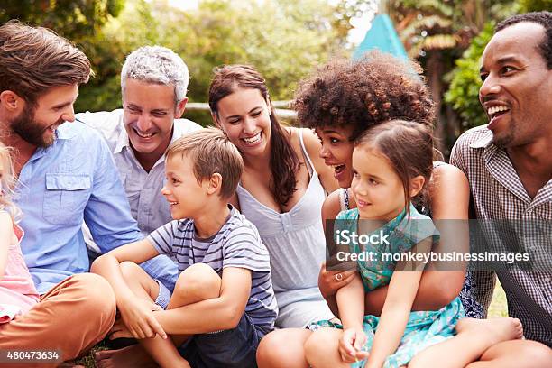 Adults And Kids Sitting On The Grass In A Garden Stock Photo - Download Image Now - Multiracial Group, Friendship, Multiracial Person