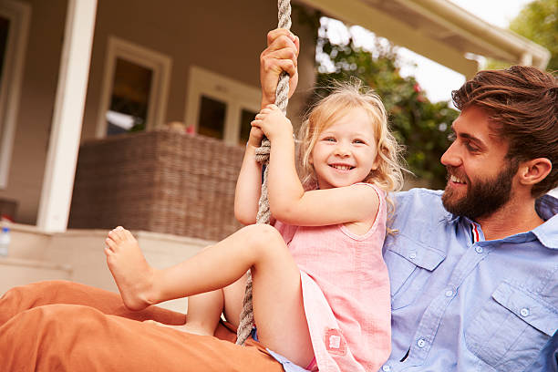 istock Father playing with daughter on a rope swing in garden 480473724