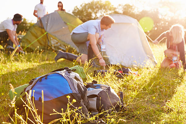 Group Of Young Friends Pitching Tents On Camping Holiday Group Of Young Friends Pitching Tents On Camping Holiday music festival camping summer vacations stock pictures, royalty-free photos & images