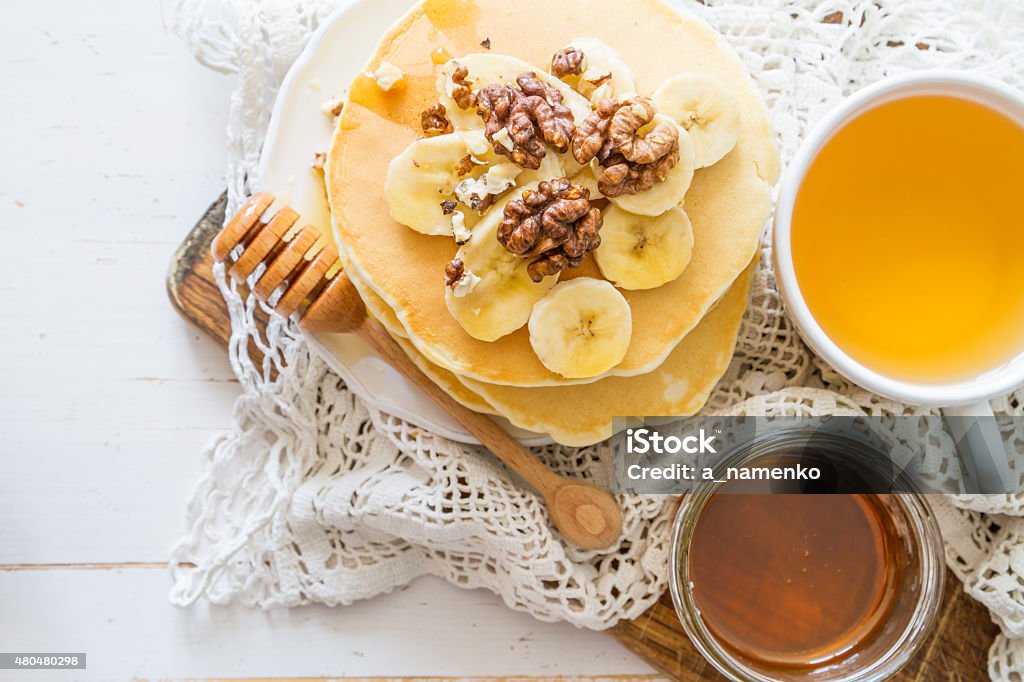 Pancakes with banana, nuts, honey, white wood background Pancakes with banana, nuts, honey, white wood background, top view 2015 Stock Photo