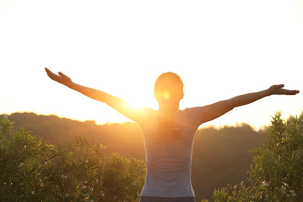 istock cheering woman open arms to sunrise 480482309