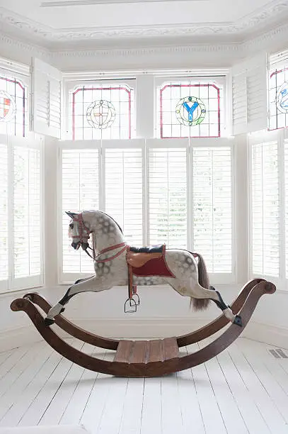 Antique rocking horse in bay window with stained glass