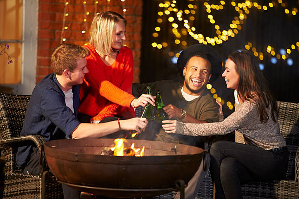 istock Group Of Friends Enjoying Evening Drinks By Firepit 480486448
