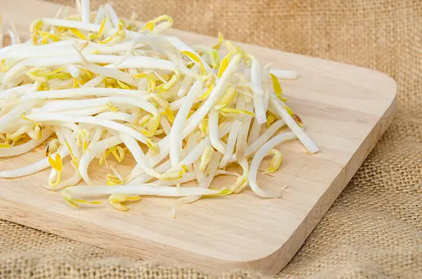 Mung beans or bean sprouts in wooden dish on sackground.