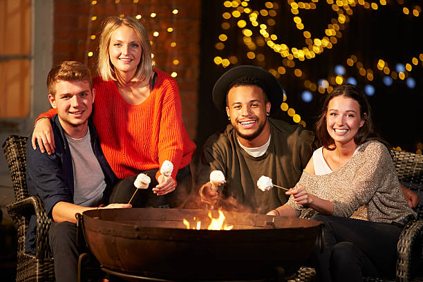 istock Group Of Friends Toasting Marshmallows By Firepit 480486460