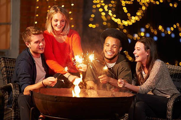 istock Group Of Friends Lighting Sparklers By Firepit 480486462