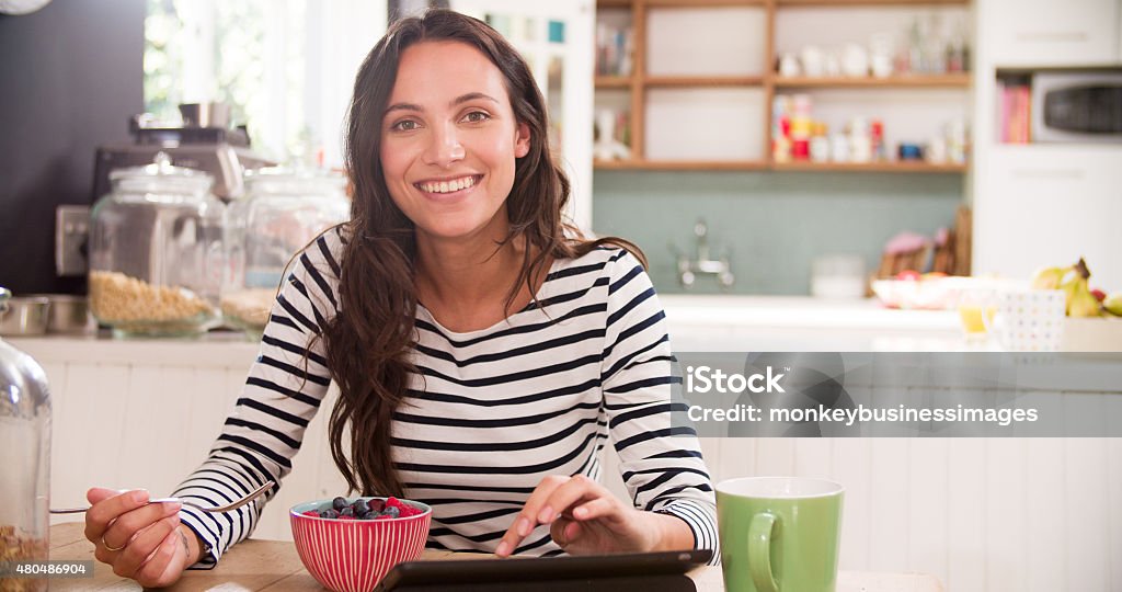 Young Woman Eating Breakfast Whilst Using Digital Tablet Women Stock Photo