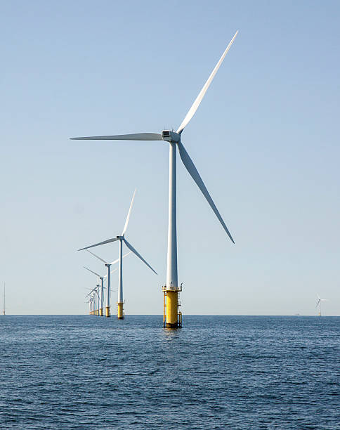 Line up of 12 off shore wind turbines One row of 12 wind turbines in an offshore wind farm in the North Sea just off the coast of the Netherlands, on a clear day. offshore wind farm stock pictures, royalty-free photos & images