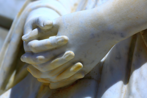 Detail of marble Virgin Mary praying hands statue in a public cemetery of Southern Brazil.