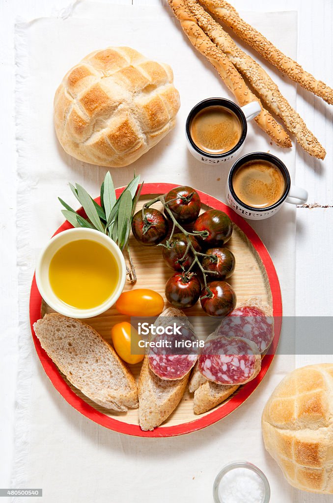 Italian snack lunch. Black Sicilian tomatoes, salami, bread in t Italian snack lunch. Black Sicilian tomatoes, salami, bread in the form of a turtle, bread sticks with sesame seeds 2015 Stock Photo