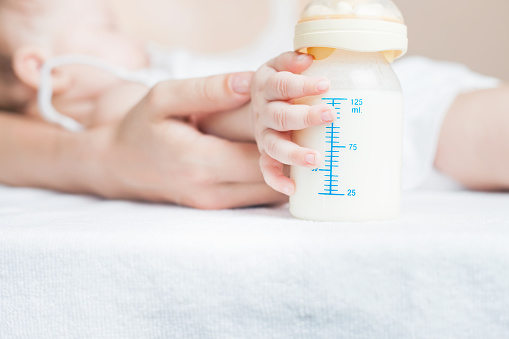 istock Baby holding a baby bottle with breast milk 480500794