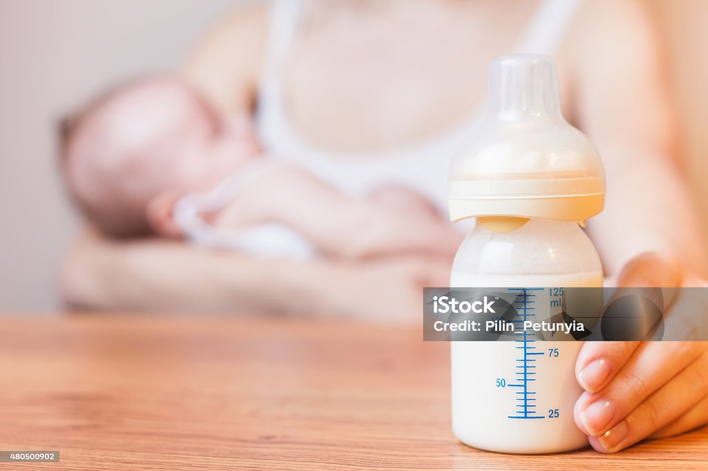 Mother holding a baby bottle with breast milk Mother holding a baby bottle with breast milk for breastfeeding at foreground, mothers breast milk is the most healthy food for newborn baby Baby Bottle Stock Photo