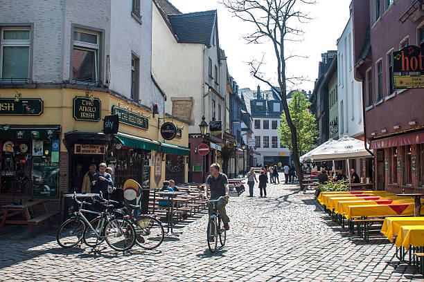 Scene Of Building Exterior, People Walking Around, Looking Around, Sitting Down, Eating And Drinking In A Restaurant During Summer Season At Aachen City Center In North Rhine Westphalia Germany Europe