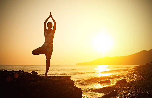 istock woman doing yoga on the beach at sunset 480509253