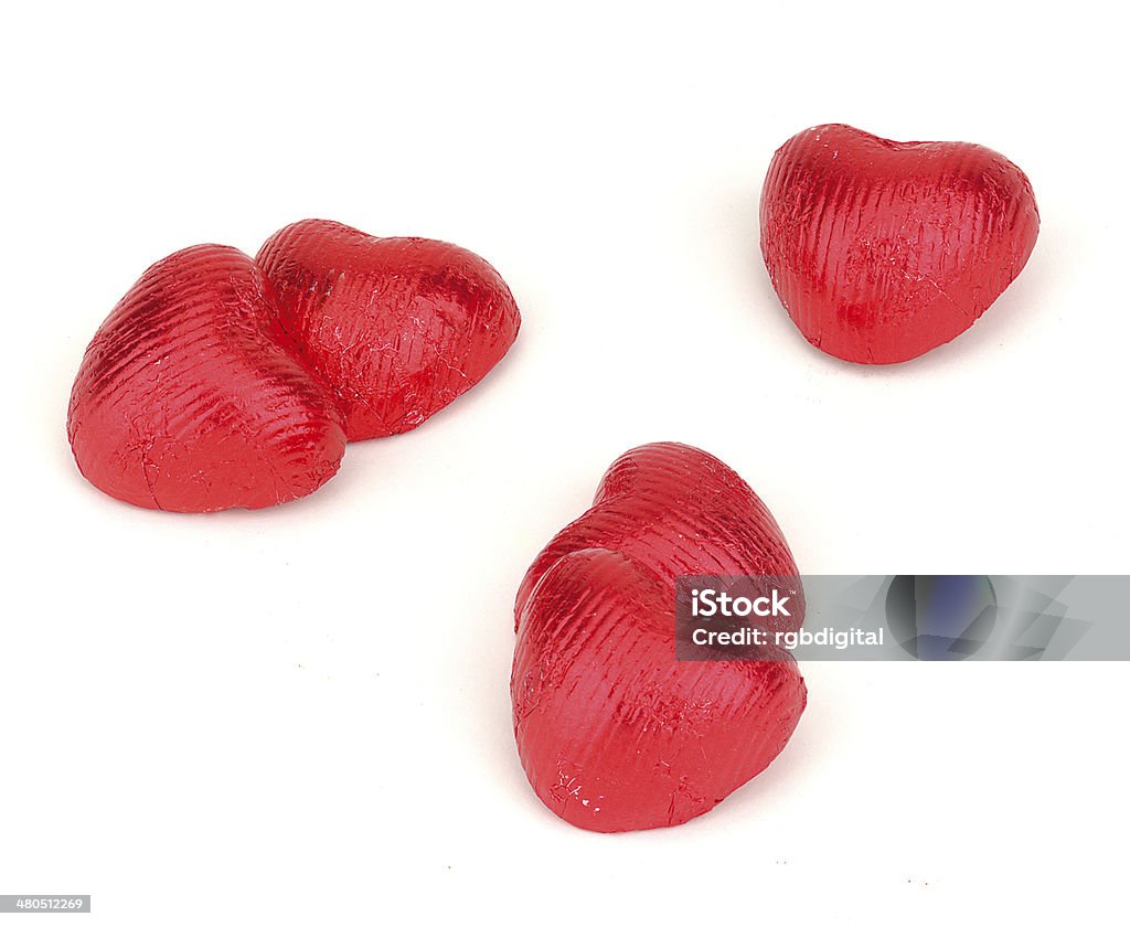 Red heart chocolates Five heart chocolates in red foil wrappers. Candy Stock Photo