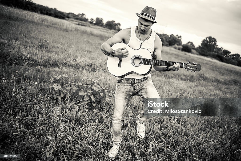 Country guitarist playing the guitar in field Country guitarist playing the aquistic guitar in field/black and white 2015 Stock Photo