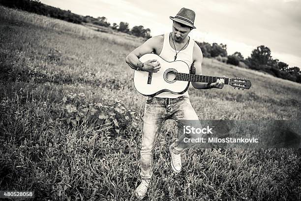 Country Guitarist Playing The Guitar In Field Stock Photo - Download Image Now - 2015, Acoustic Guitar, Acoustic Music