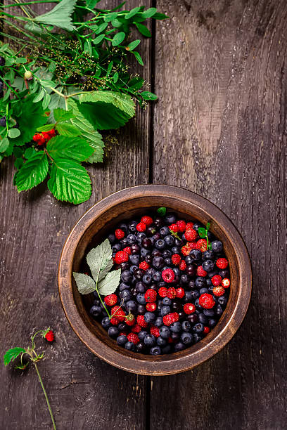 istock Wooden bowl with wild berries on wooden table. 480535772