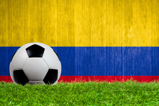 Soccer ball on grass with Colombia flag background close up