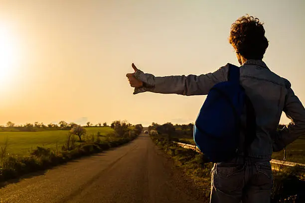 Young Man Hitchhiking on a Country Road