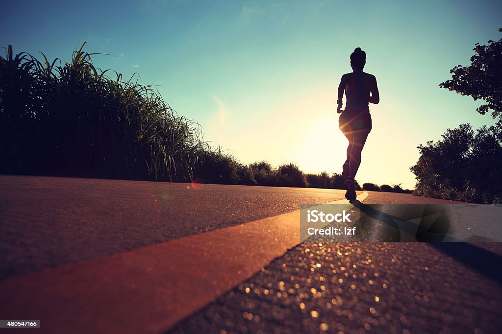 young fitness woman running on sunrise seaside trail Marathon Stock Photo