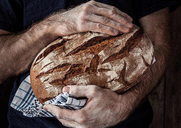 istock Baker man holding rustic loaf of bread in hands 480550013