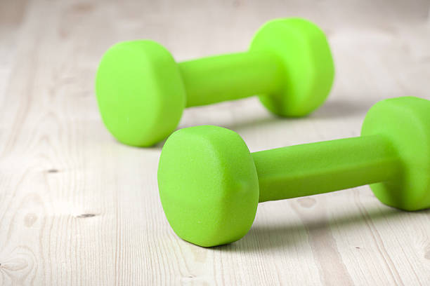 istock small green dumbbells on wooden surface 480551353