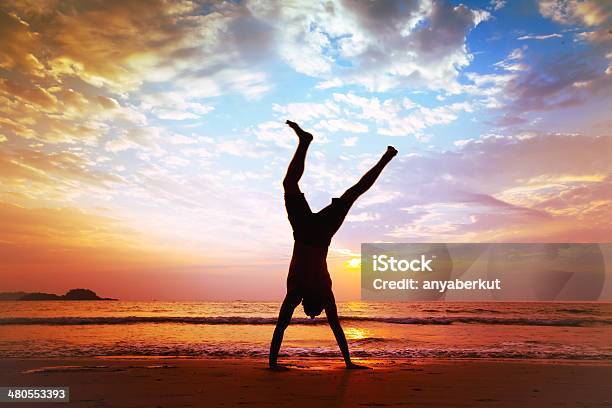 Man Does Handstand On Beach At Sunset Stock Photo - Download Image Now - Joy, Jumping, Beach