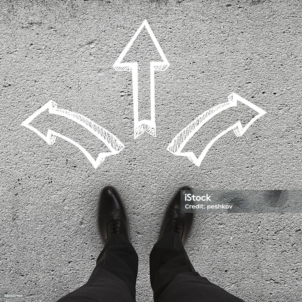 feet and arrows pair of feet standing on a tarmac road with arrows Adult Stock Photo